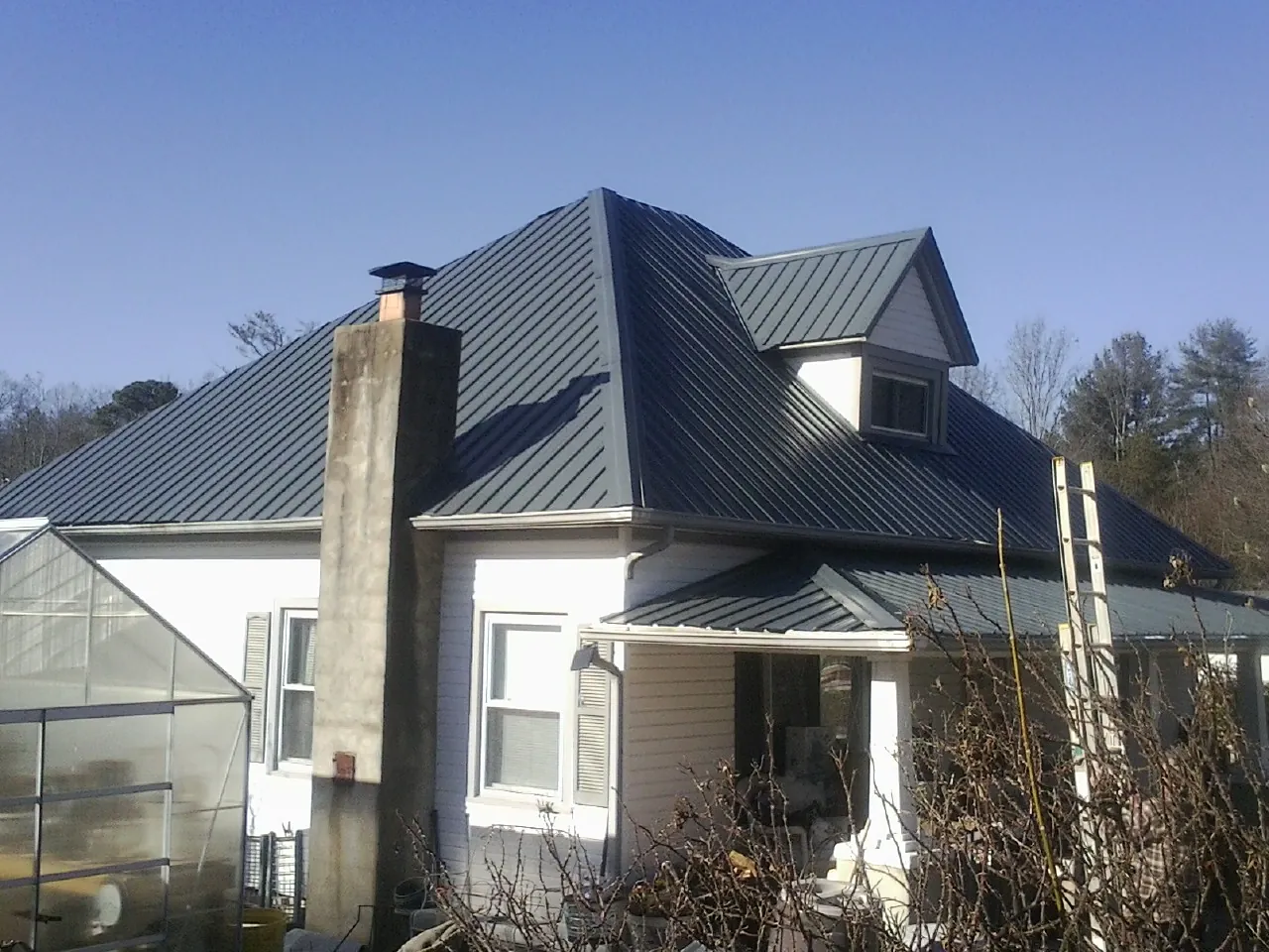 Dark blue standing seam metal roof on a white farmhouse with dormer — Slate & Tile Roof Repair by Roofing Brothers in Finleyville