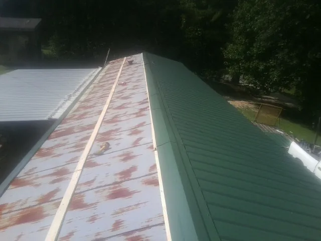 Old rusted panels beside newly installed green metal roofing — Wind Damage Roof Repair by Roofing Brothers in Finleyville