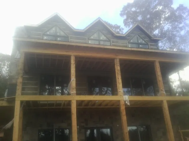 Dormers and porch framing on a large log home under construction — Roof Coating work by our crew in Finleyville
