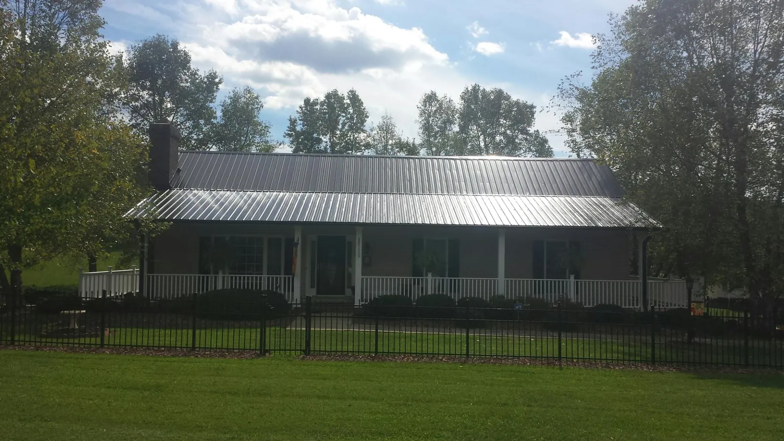 Gray metal roof on a brick ranch with a full width front porch — Gutter Guard Installation work by our crew in Finleyville