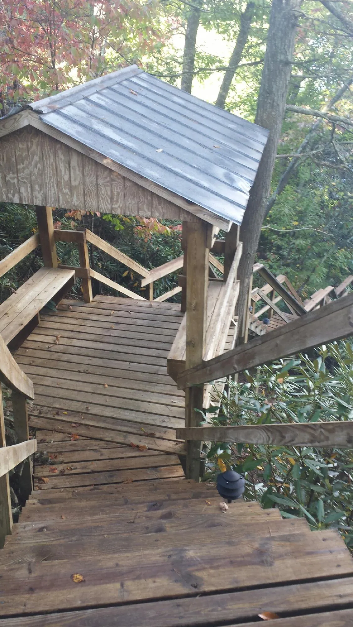 Metal roofed shelter over wooden steps on a wooded walkway — Skylight Repair & Installation work by our crew in Finleyville