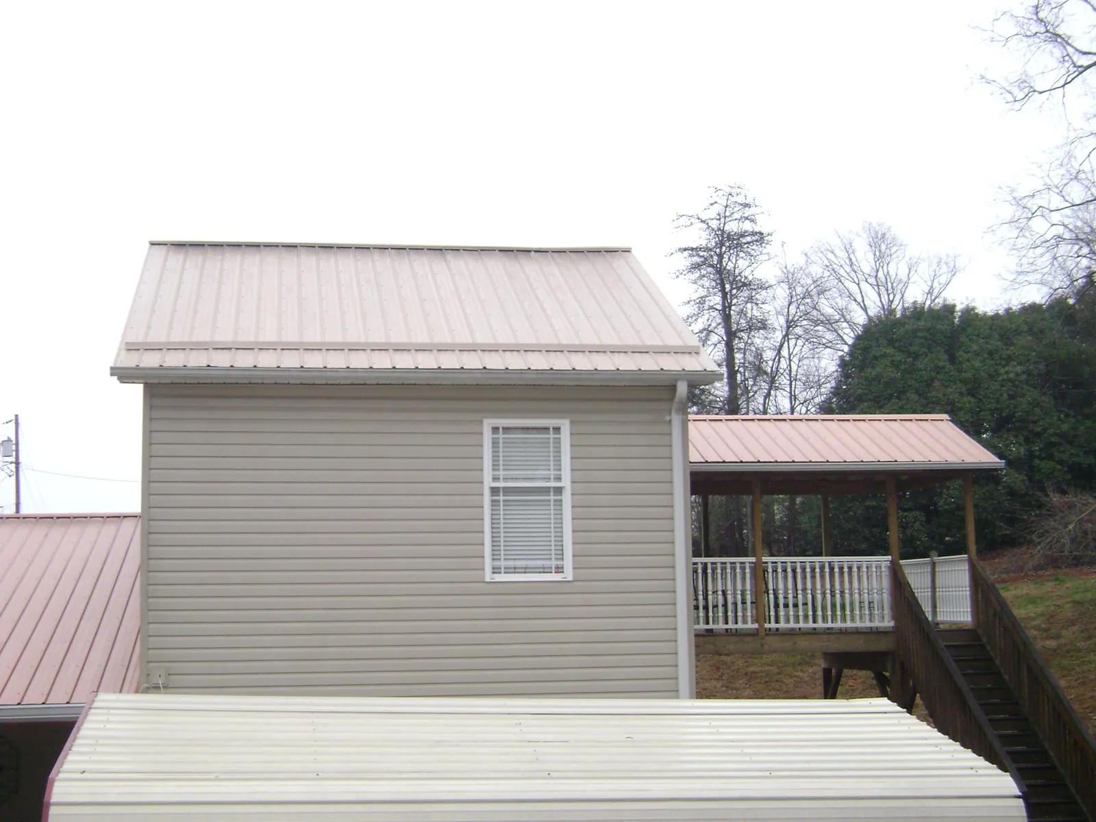Tan metal roofs on a two story addition and attached porch, from a Roof Replacement job in Finleyville