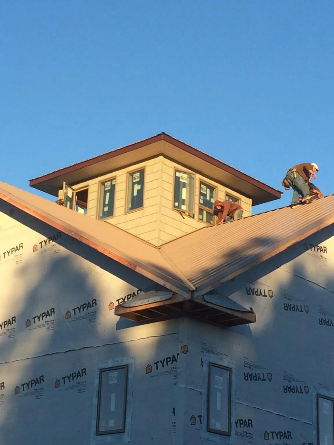 Roofers working around a rooftop cupola on a new metal roof at sunset — Roof Waterproofing in Finleyville by Roofing Brothers